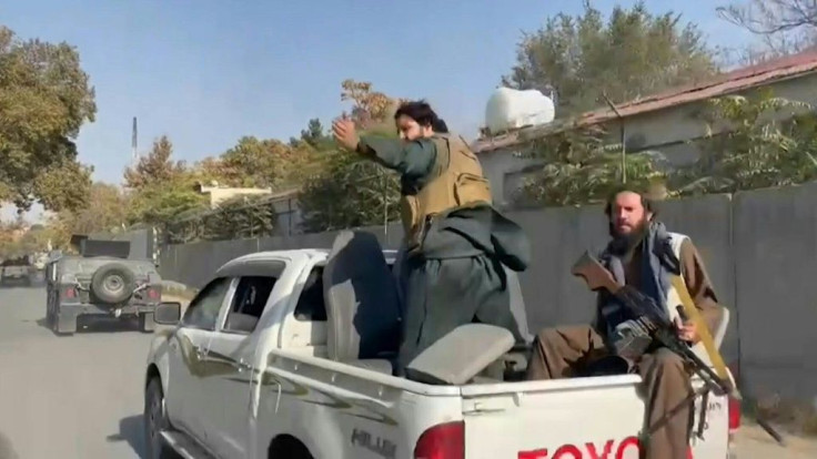 Afghan Taliban security force rushes through traffic after explosions and gunfire were heard near a Kabul military hospital. Smoke seen rising in a distance.