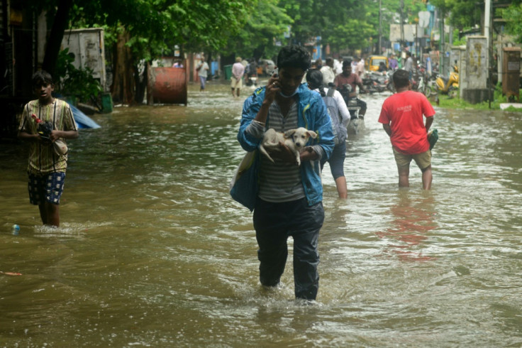 People wade through a flooded street after heavy rain across Chennai in southern India