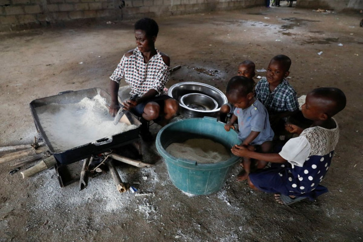 Chinyere Isaiah, a flood victim, fries cassava flakes at a school converted to relief camp in Ogbogu, following a massive flood in Rivers state